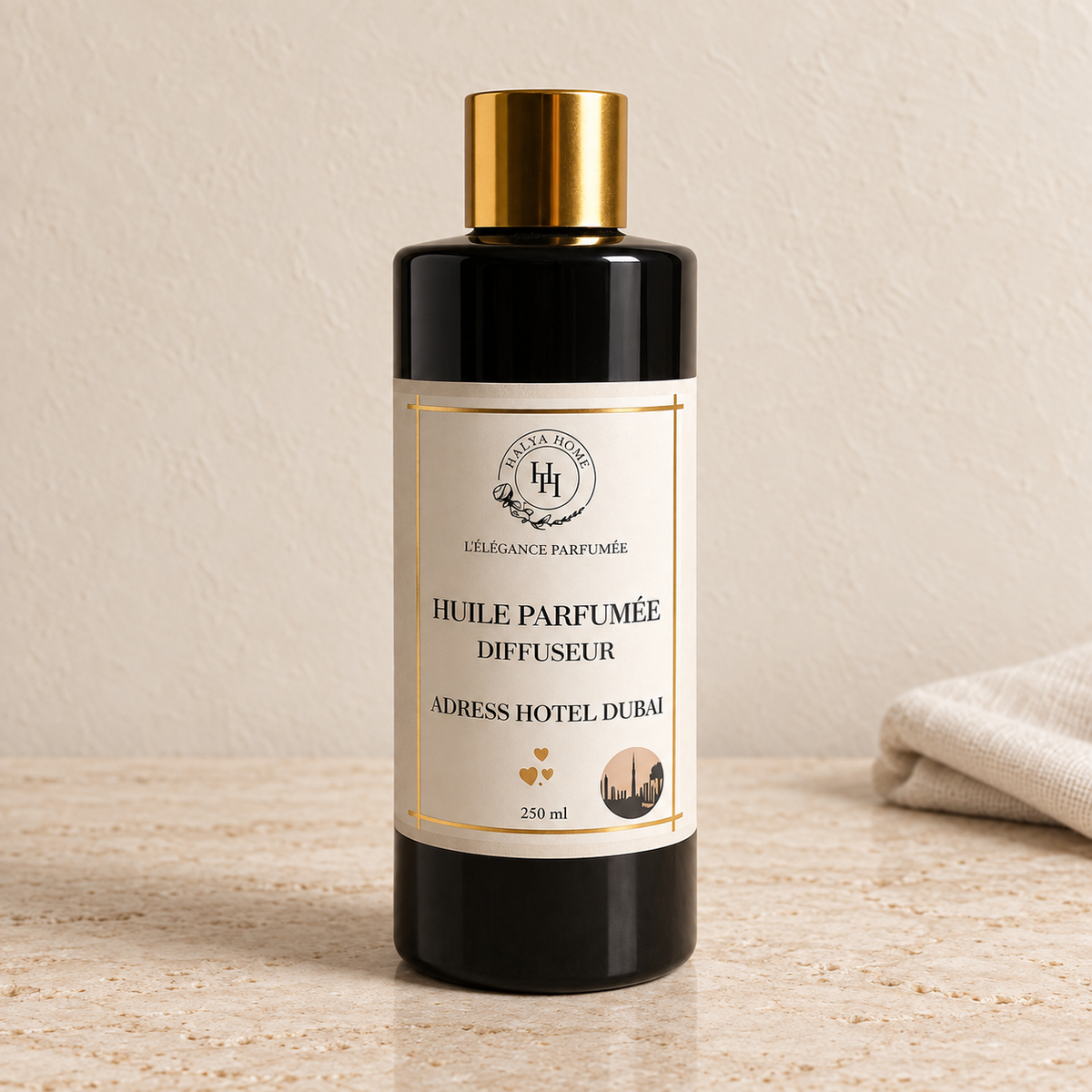 Huile parfumée Adress Dubaï Halya Home pour diffuseur électrique, flacon noir de 250 ml à bouchon doré dans un décor ivoire et travertin.