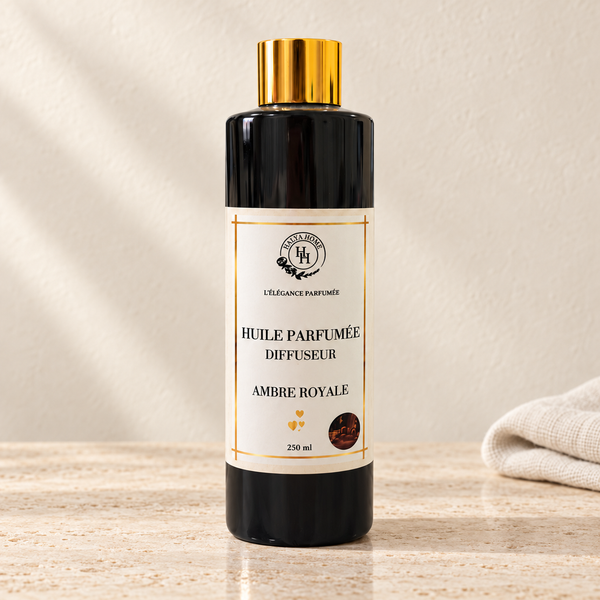 Huile parfumée Ambre Royale Halya Home pour diffuseur électrique, flacon noir de 250 ml à bouchon doré sur du travertin clair dans un décor ivoire.