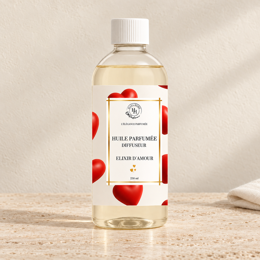 Huile parfumée Élixir d’Amour Halya Home pour diffuseur électrique, flacon transparent de 250 ml à bouchon blanc et étiquette à cœurs rouges sur du travertin.
