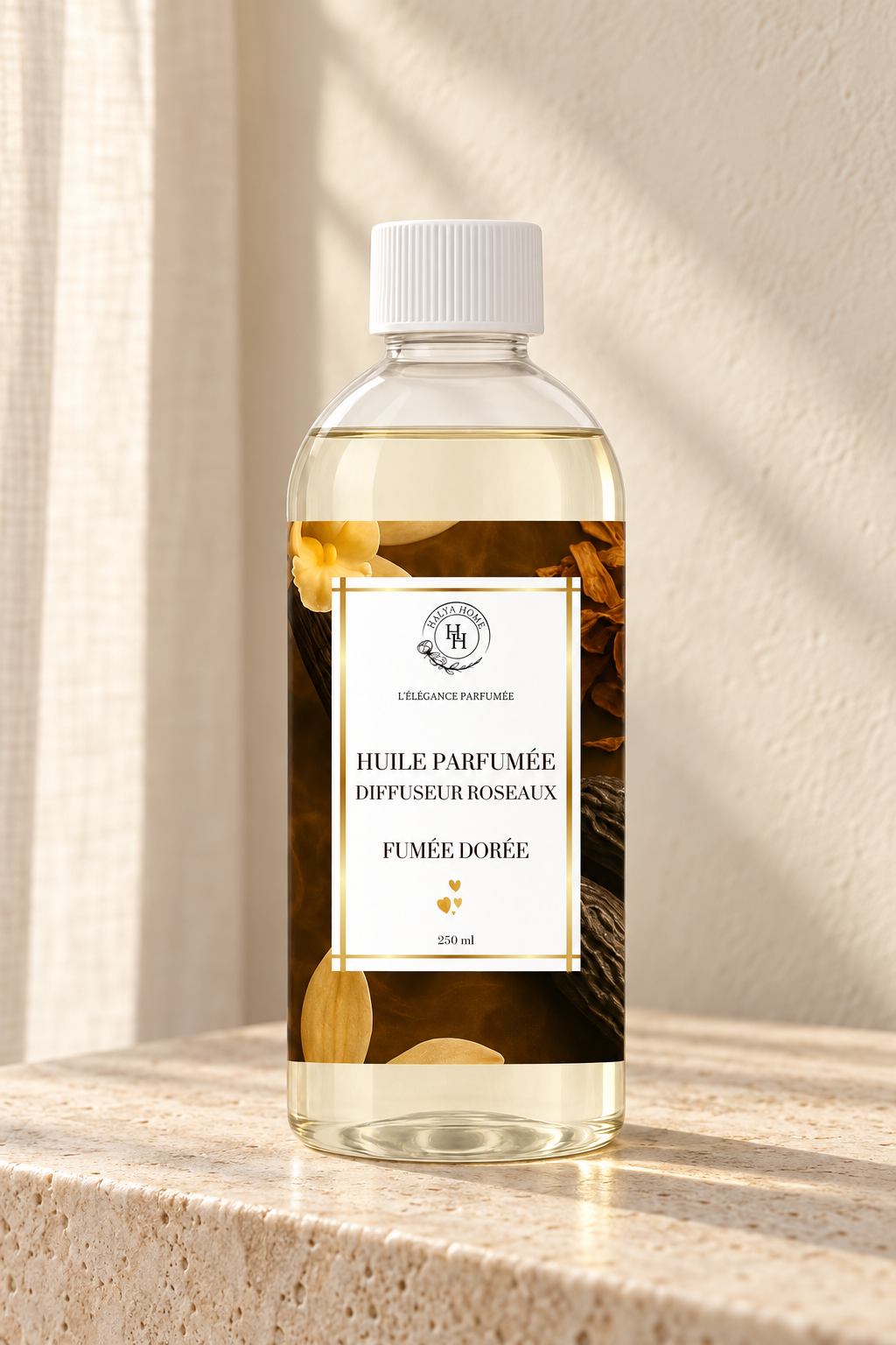 Huile parfumée Fumée Dorée Halya Home pour diffuseur à roseaux, flacon de 250 ml sur du travertin dans un décor ivoire.