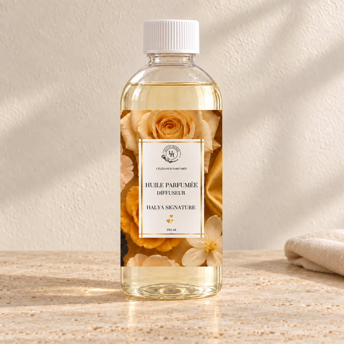 Huile parfumée Halya Signature Halya Home pour diffuseur électrique, flacon transparent de 250 ml à bouchon blanc et étiquette florale dorée sur du travertin.