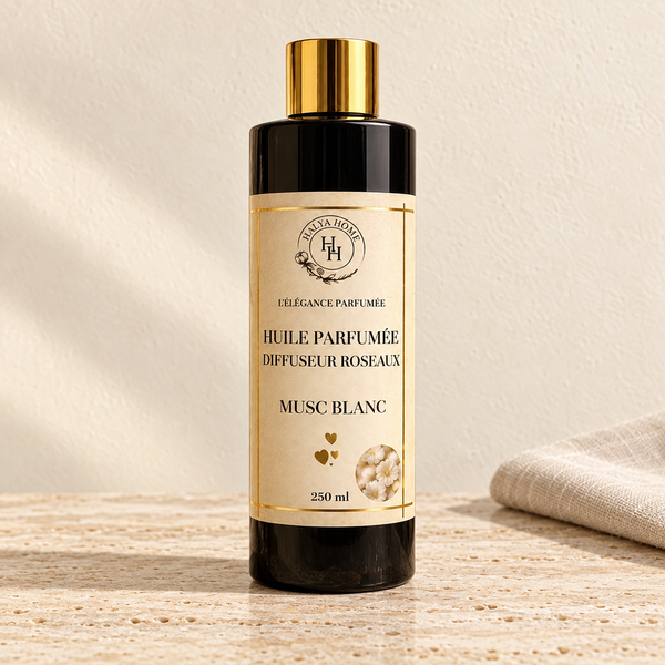 Huile parfumée Musc Blanc Halya Home pour diffuseur à roseaux, flacon noir de 250 ml à bouchon doré sur du travertin clair dans un décor ivoire.