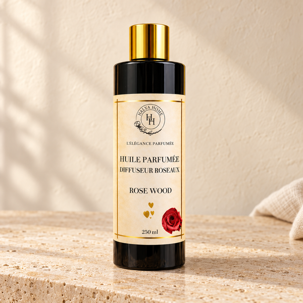 Huile parfumée Rose Wood Halya Home pour diffuseur à roseaux, flacon noir de 250 ml avec bouchon doré sur une pierre claire.