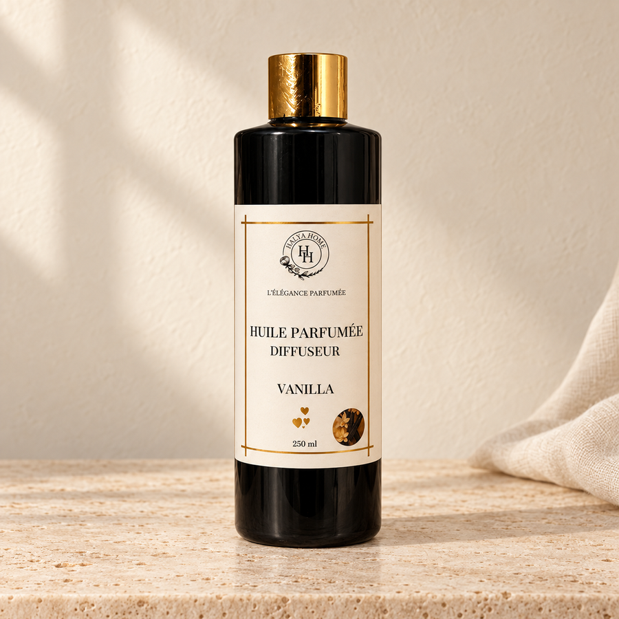 Huile parfumée Vanilla Halya Home pour diffuseur électrique, flacon noir de 250 ml à bouchon doré dans un décor ivoire et travertin.