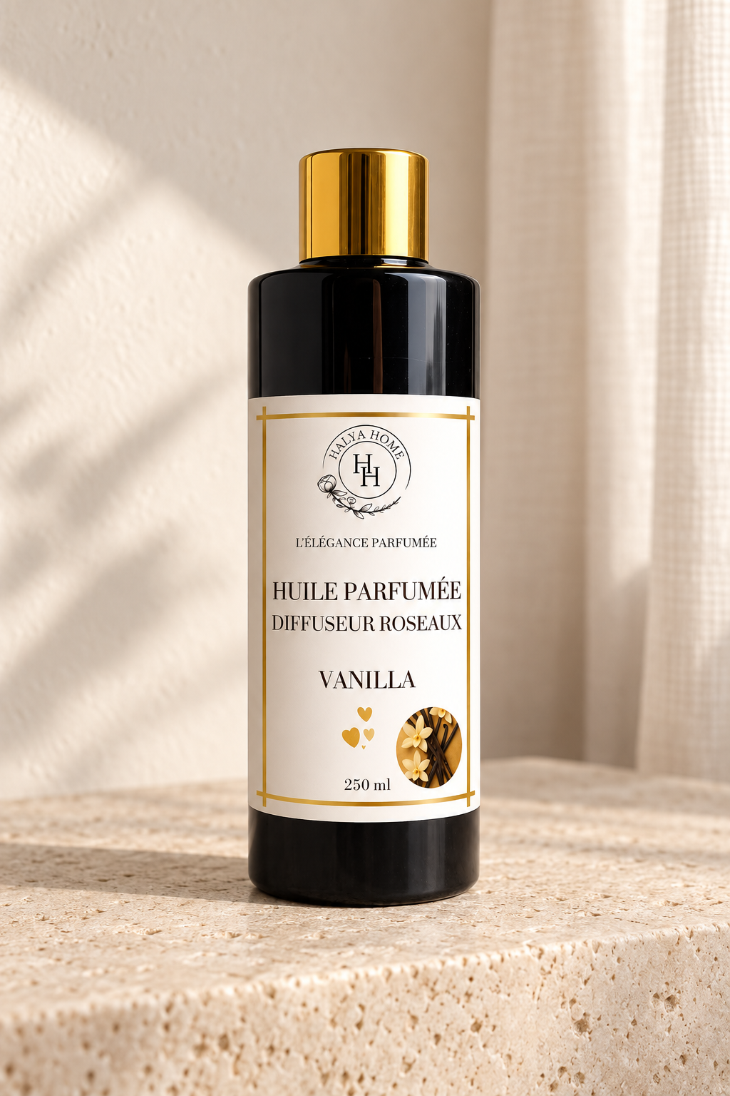Huile parfumée Vanilla Halya Home pour diffuseur à roseaux, flacon noir et doré de 250 ml sur une console en travertin.