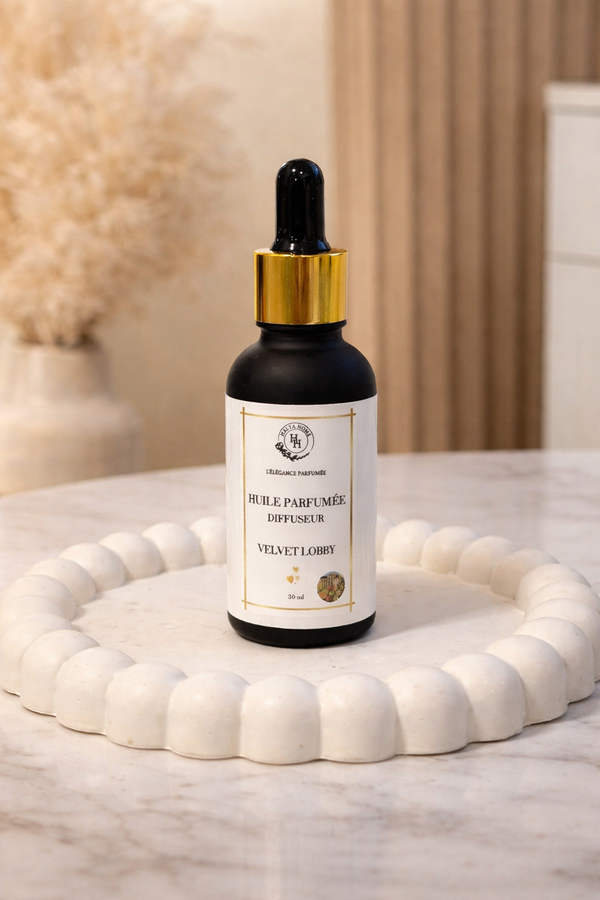 Huile parfumée Velvet Lobby Halya Home 30 ml, flacon noir compte-gouttes à bague dorée sur un plateau crème.