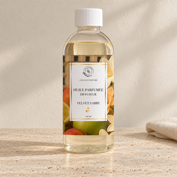 Huile parfumée Velvet Lobby Halya Home pour diffuseur électrique, flacon transparent de 250 ml à bouchon blanc et étiquette fruitée et florale sur du travertin.