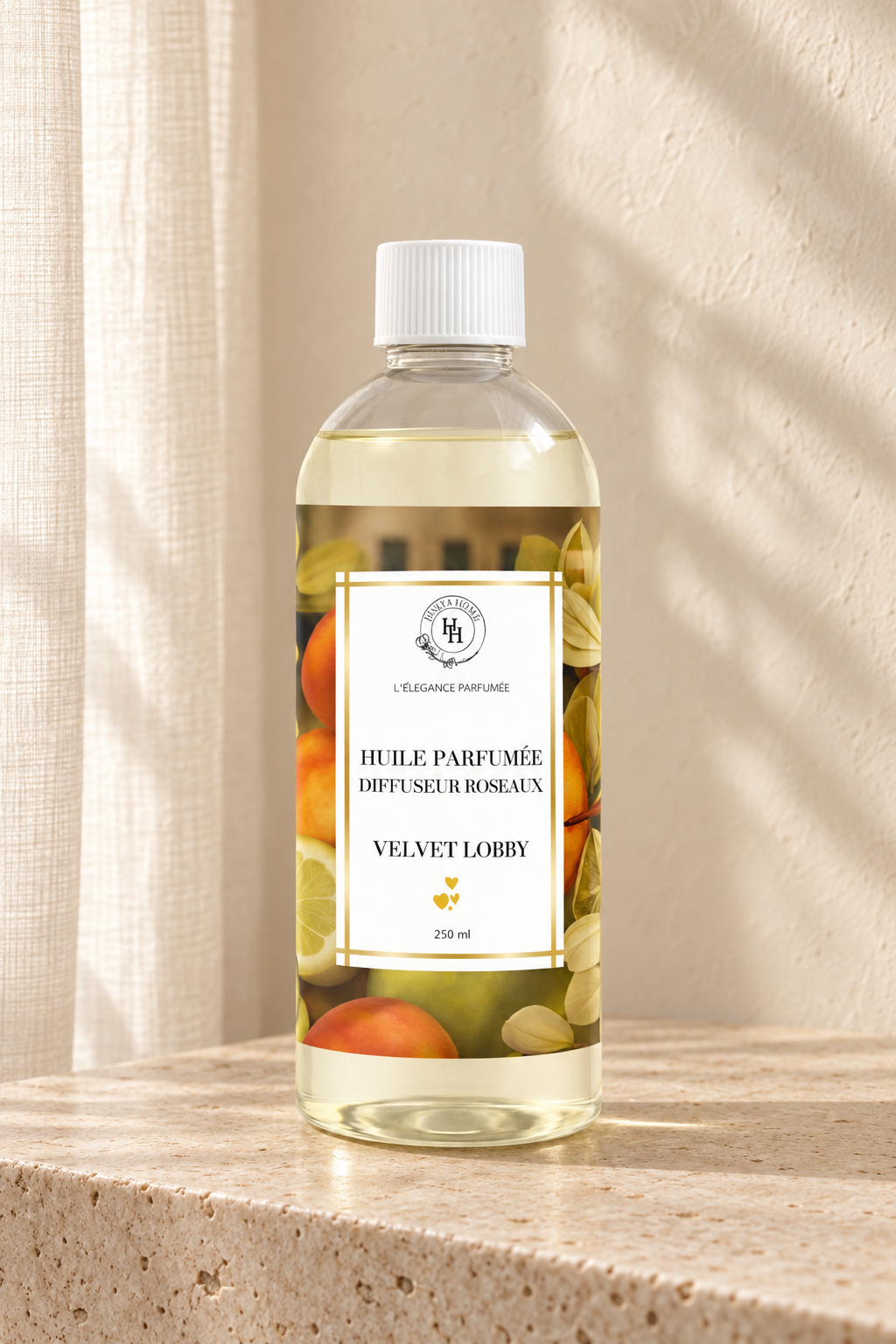 Huile parfumée Velvet Lobby Halya Home pour diffuseur à roseaux, flacon de 250 ml sur une console en travertin dans un décor ivoire.