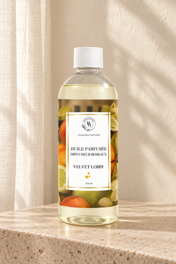 Huile parfumée Velvet Lobby Halya Home pour diffuseur à roseaux, flacon de 250 ml sur une console en travertin dans un décor ivoire.