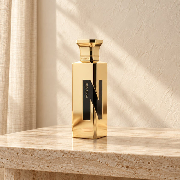 Paris Oud de Naseem 75 ml, flacon doré sur une console en travertin clair — Halya Home.