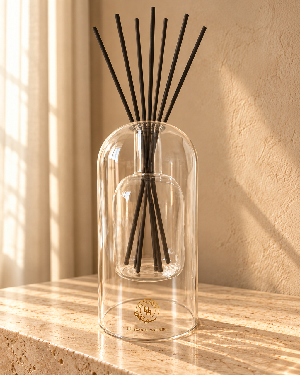 Diffuseur à roseaux Sculpt 01 HALYA HOME en verre transparent de 220 ml, avec six bâtonnets noirs en éventail, sur du travertin.
