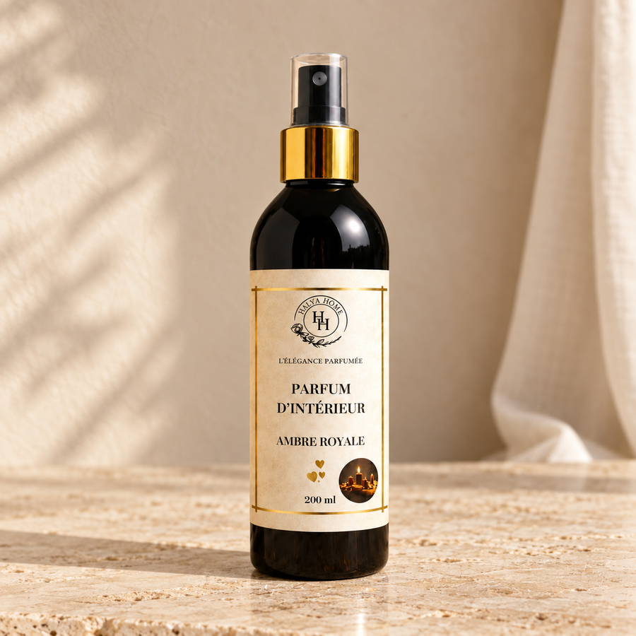 Spray d’intérieur Ambre Royale Halya Home 200 ml, flacon noir avec bague dorée et capuchon transparent dans un décor ivoire et travertin.