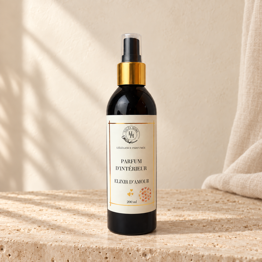 Spray d’intérieur Élixir d’Amour Halya Home 200 ml, flacon noir à bague dorée présenté sur du travertin dans un décor ivoire.