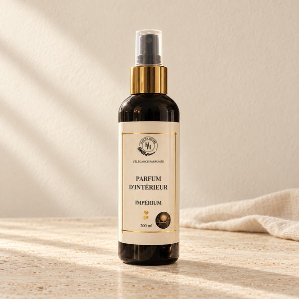 Spray d’intérieur Impérium Halya Home 200 ml, flacon sombre à bague dorée et capuchon transparent sur du travertin clair dans un décor ivoire.