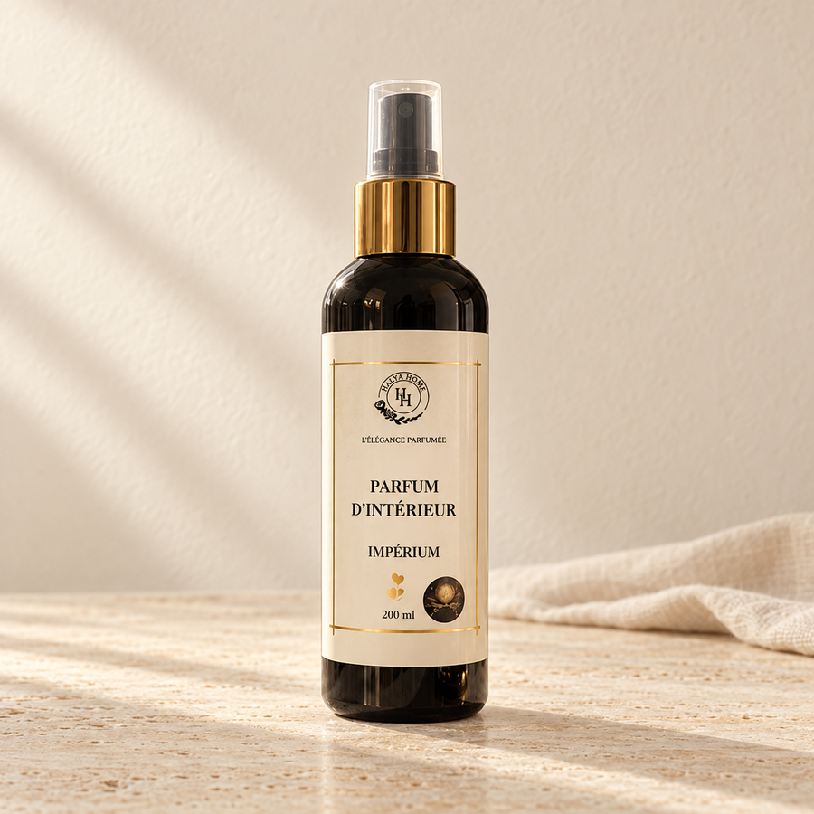 Spray d’intérieur Impérium Halya Home 200 ml, flacon sombre à bague dorée et capuchon transparent sur du travertin clair dans un décor ivoire.
