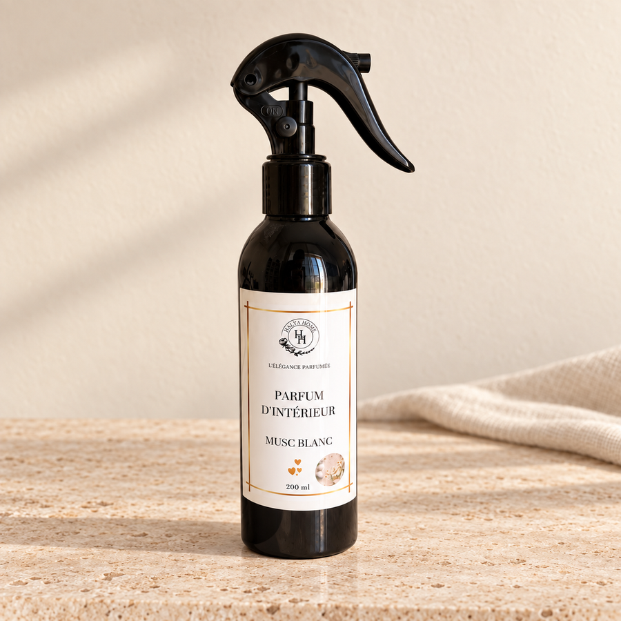 Spray d’intérieur Musc Blanc Halya Home 200 ml, flacon noir avec gâchette sur une pierre claire dans un décor ivoire et lin.
