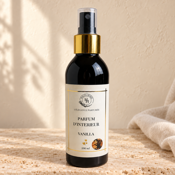 Spray d’intérieur Vanilla Halya Home 200 ml, flacon noir avec bague dorée et capuchon transparent sur une pierre beige.