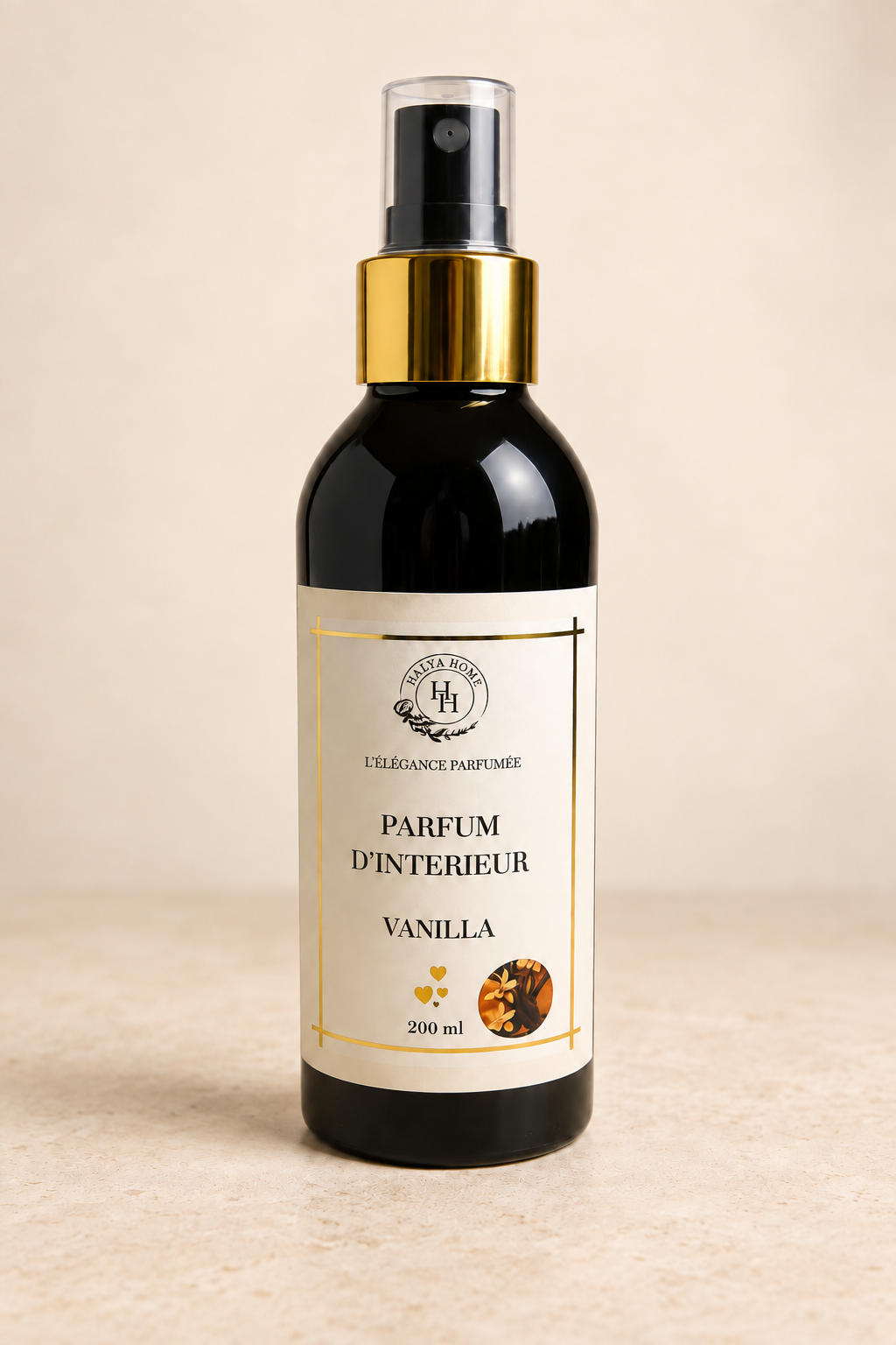 Spray d’intérieur Vanilla Halya Home 200 ml, flacon noir avec bague dorée et capuchon transparent, présenté de face sur fond ivoire.